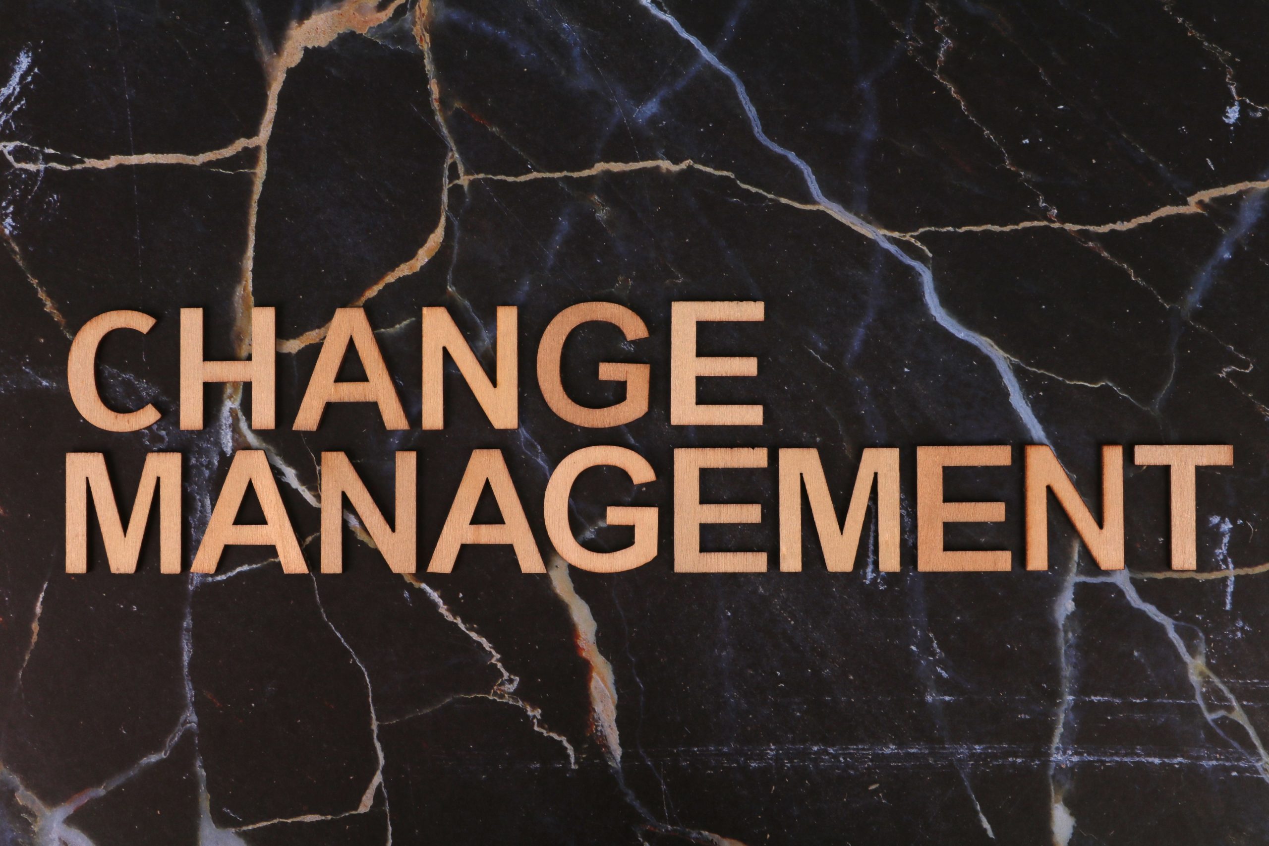 Wooden letters spelling 'Change Management' on a dark marble surface