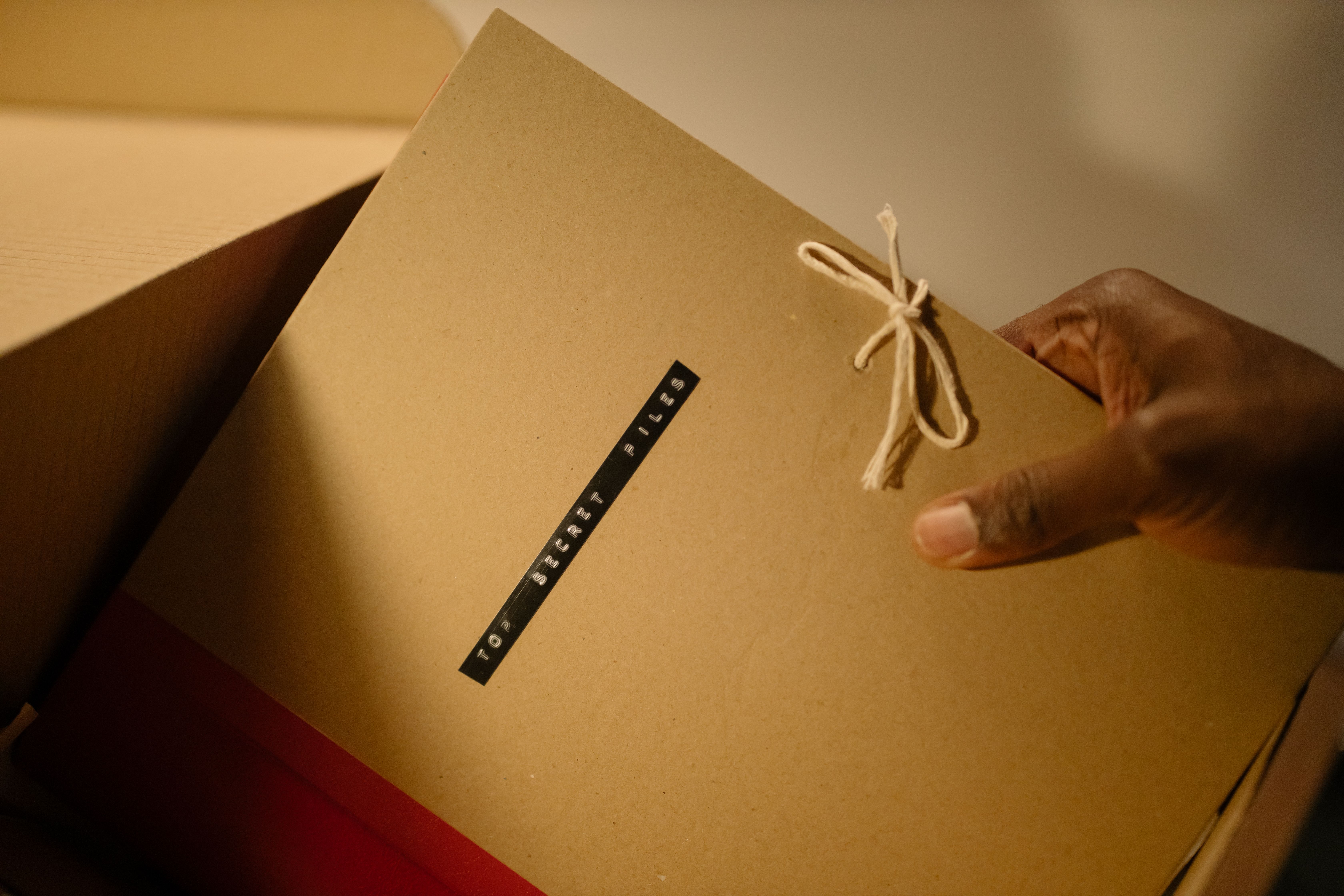 Hand holding a top secret document folder, illustrating confidential client information and privacy controls.