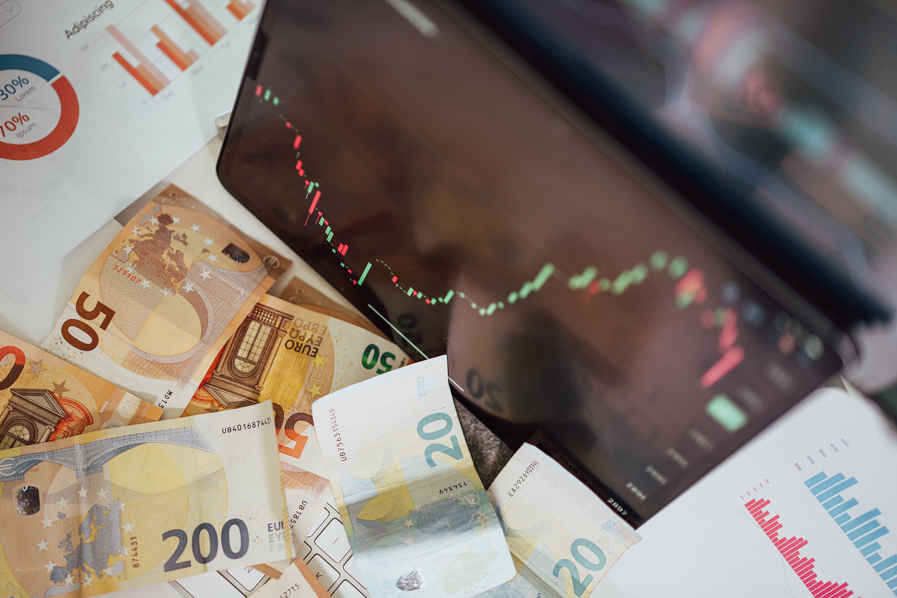 Euro banknotes with a stock market chart showing a downward trend, representing economic volatility