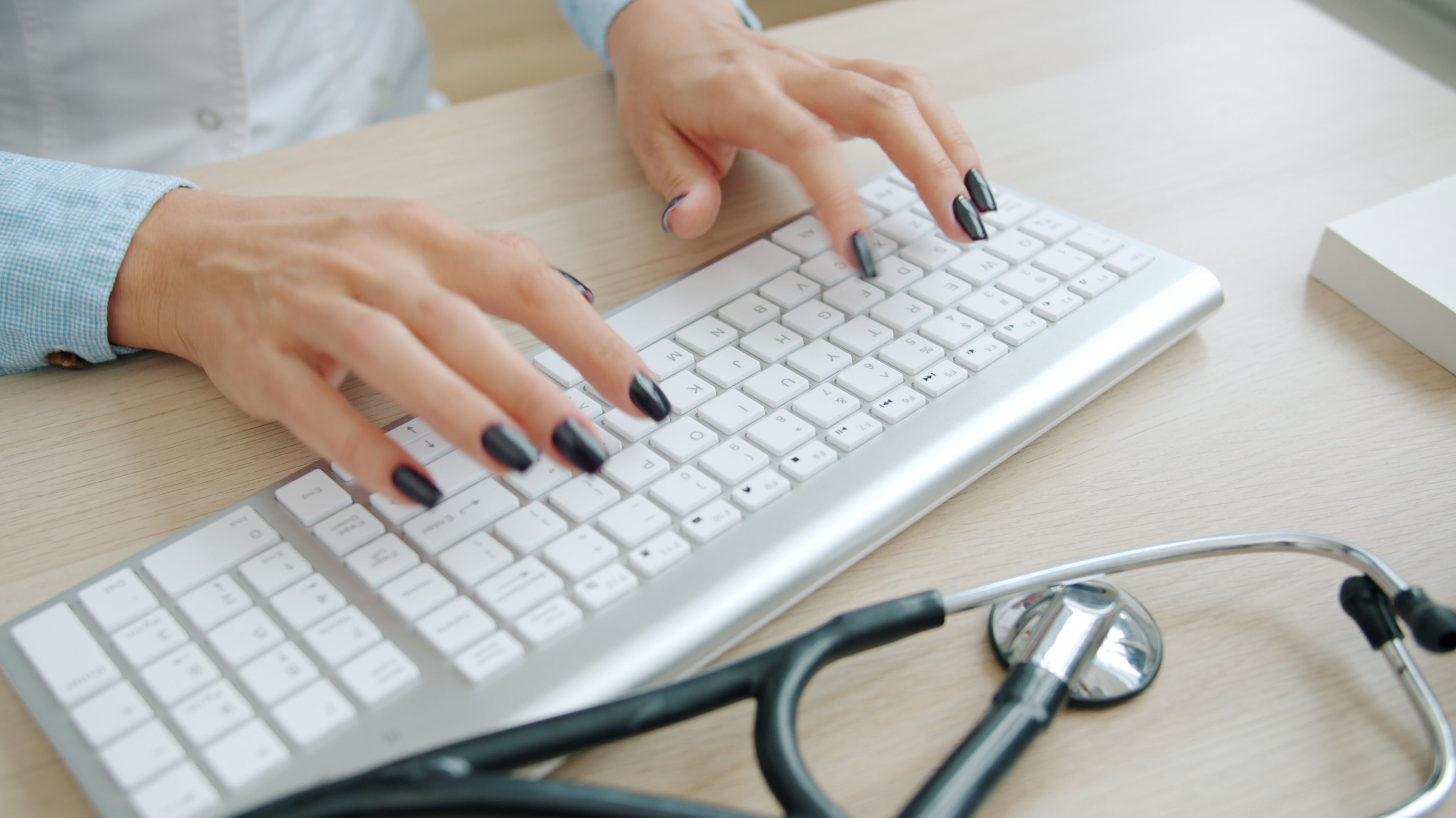 Doctor typing at a computer with a stethoscope nearby, representing privacy safeguards for sensitive healthcare data.