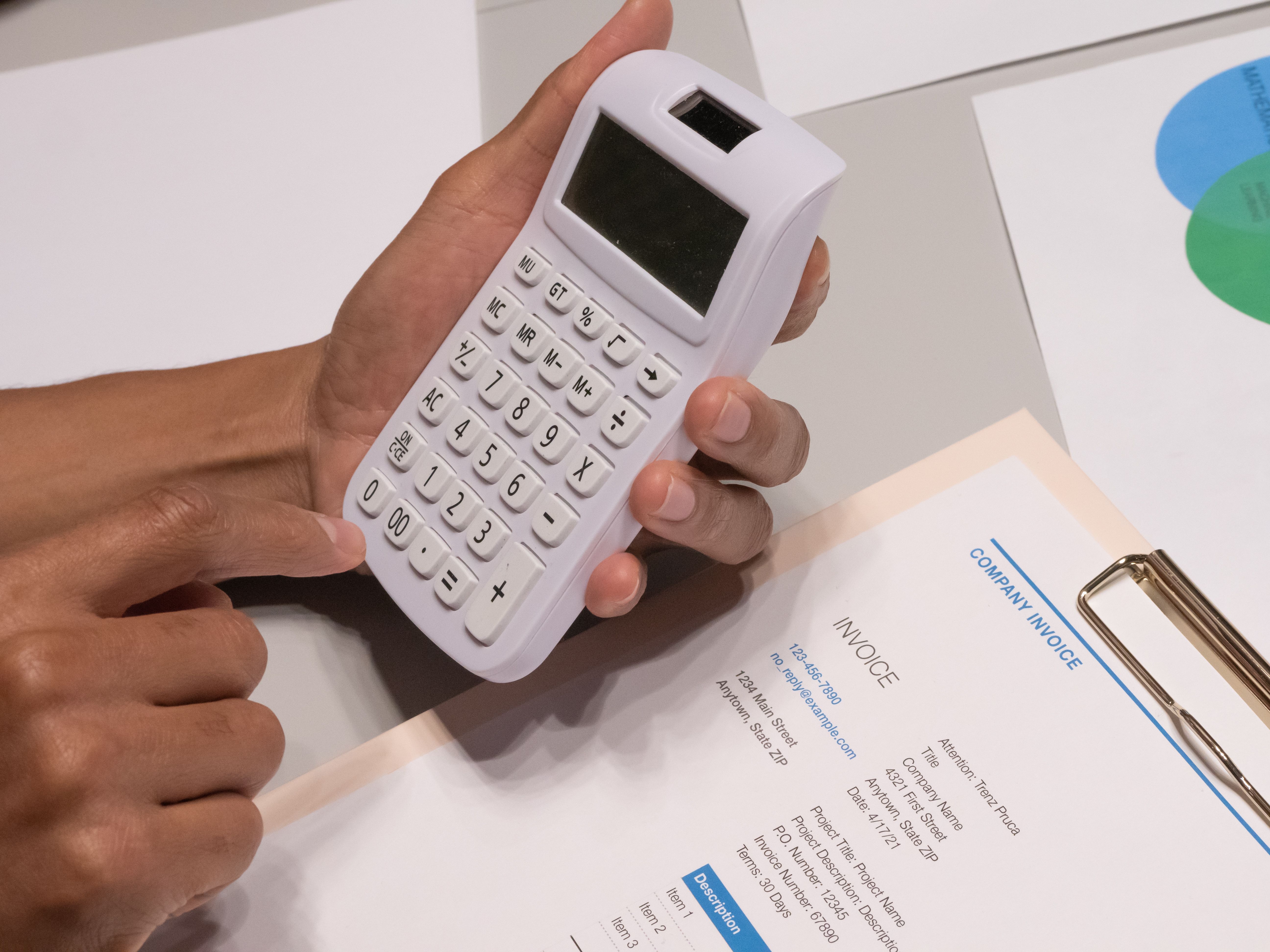 Hands using a calculator beside an invoice to illustrate legal billing and fee calculations