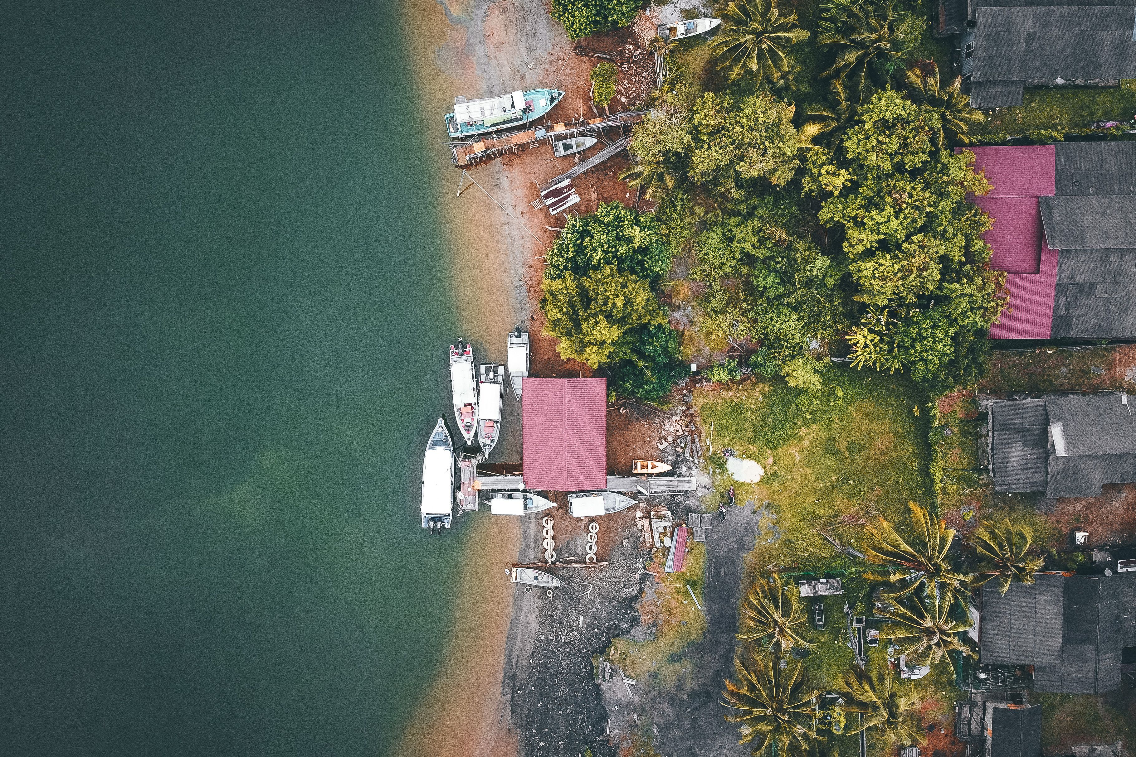 Boats and coastal homes along a tropical shoreline, illustrating Sabah's maritime communities and coastal identity.